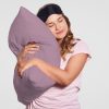 Photo of attractive European woman with healthy skin leans on soft pillow, wears pyjamas, eyewear on head, poses alone against white background, has sleepy look. People, good morning concept
